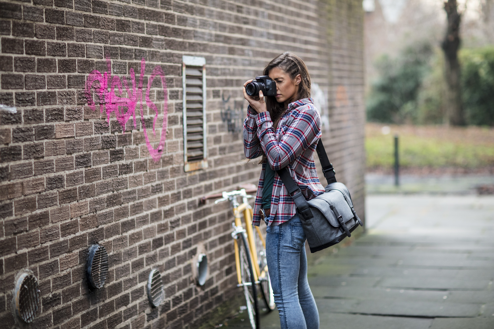 female photographer taking a picture of pink grafitti on a wall